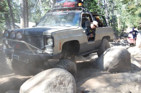 1993 Jeep Wrangler - This modified pickup truck is tackling a challenging rocky trail, with 'GO PREPARED' visible on its windshield.