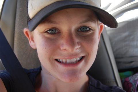 1993 Jeep Wrangler - A person smiles while wearing a baseball cap and a seatbelt inside a vehicle.