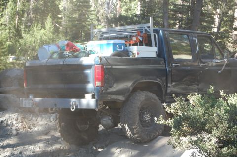 1993 Jeep Wrangler - Black pickup truck loaded with gear, parked off-road. The year appears to be around 1980.
