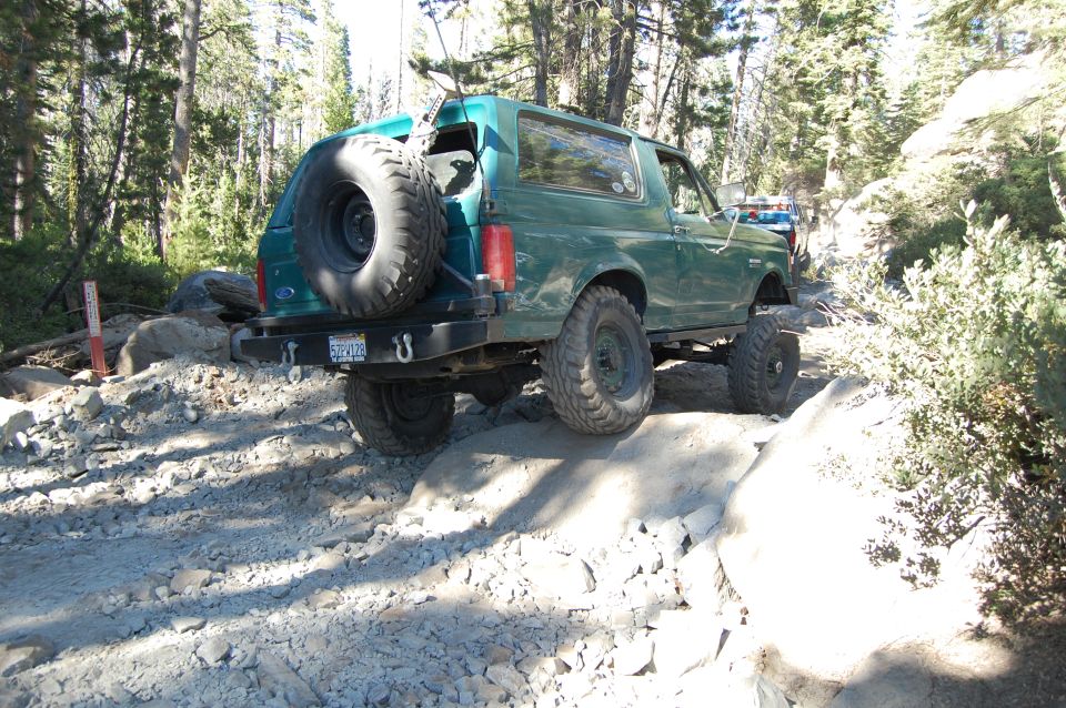 Green 1993 Ford Bronco rear view on rocky trail