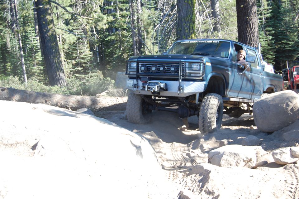 Blue pickup truck with aftermarket bumper and winch navigating rocks