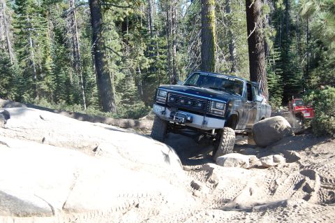 1993 Jeep Wrangler - Ford pickup truck off-roading on a rocky trail with a red Jeep in the background.