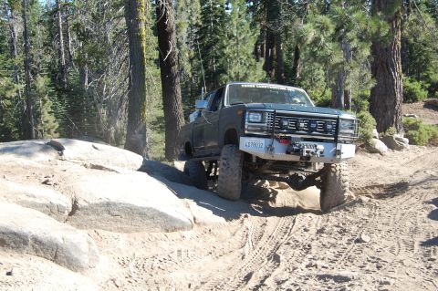 1993 Jeep Wrangler - This modified Ford pickup truck navigates a challenging off-road course with large boulders and dirt tracks.