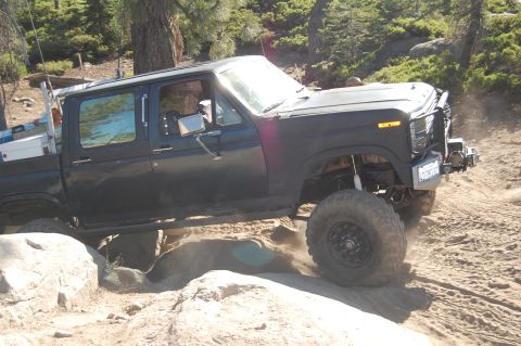 1993 Jeep Wrangler - This modified pickup truck is shown off-roading on a dirt and rock path.