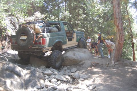 1993 Jeep Wrangler - This modified 1993 Ford Bronco navigates a challenging rocky trail with onlookers observing.