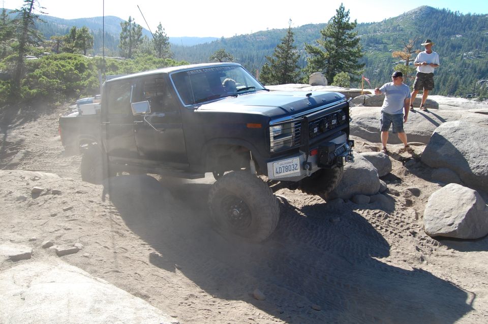 Black Ford F-Series pickup truck with off-road tires navigating rocky terrain. License plate reads 4D78032