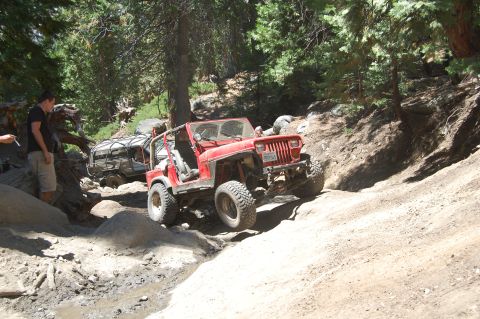 1993 Jeep Wrangler - Two Jeeps navigate a challenging off-road trail with steep inclines and rocky terrain.