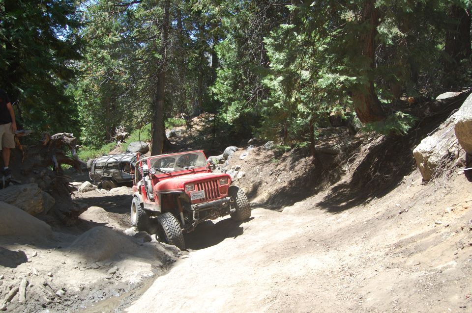 Red 1993 Jeep Wrangler on a rocky trail with another Jeep behind it