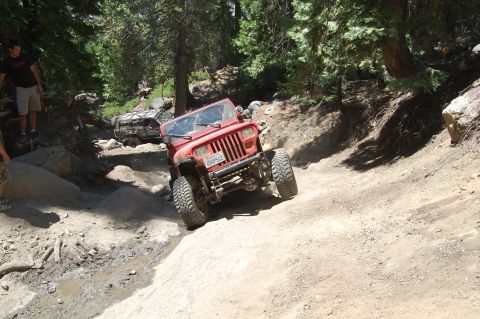 1993 Jeep Wrangler - A red Jeep Wrangler navigates a rocky off-road trail with another vehicle in the background.