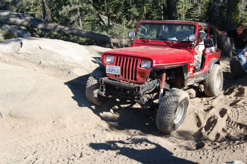 1993 Jeep Wrangler - This 1993 Jeep Wrangler navigates a rocky, sandy off-road path with a driver and passenger visible.
