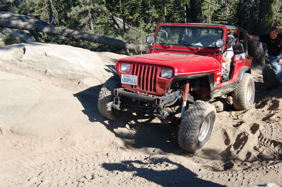 Red 1993 Jeep Wrangler on a dirt trail, front 3/4 view