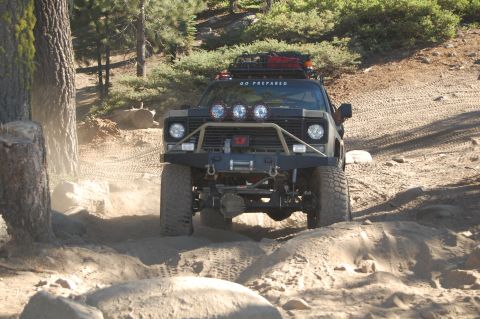 1993 Jeep Wrangler - A heavily modified truck navigates a challenging off-road course with large tires and a custom bumper.