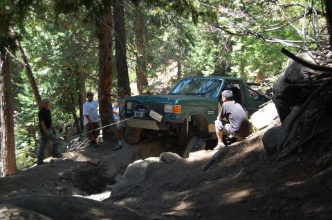 1993 Jeep Wrangler - A green 1993 Ford F-150 navigates a challenging rocky trail, assisted by a winch and several people.