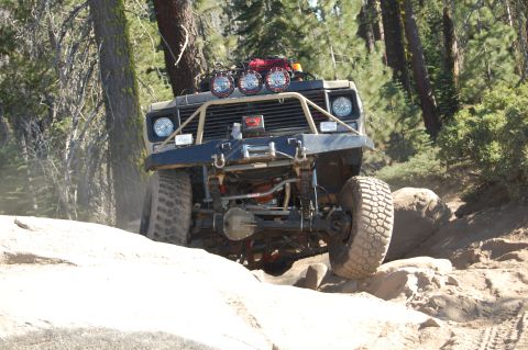 1993 Jeep Wrangler - Off-road vehicle tackling a challenging rocky path in a wooded area.