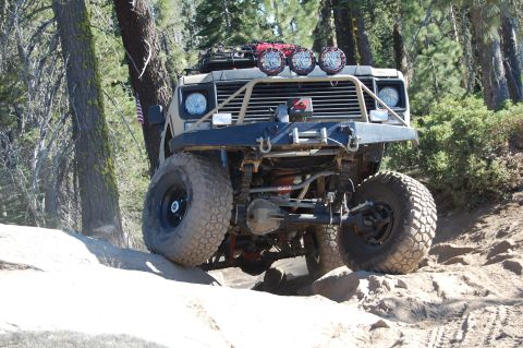 1993 Jeep Wrangler - This heavily modified vehicle navigates a challenging rocky terrain on a wooded trail.