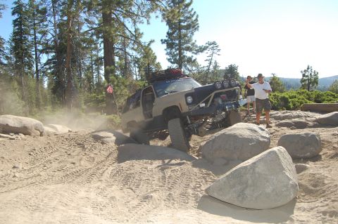 1993 Jeep Wrangler - A modified SUV tackles a challenging off-road course with spectators watching.