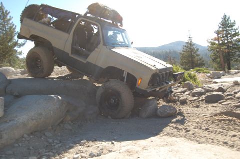 1993 Jeep Wrangler - This modified SUV is navigating a challenging rocky terrain on a sunny day.