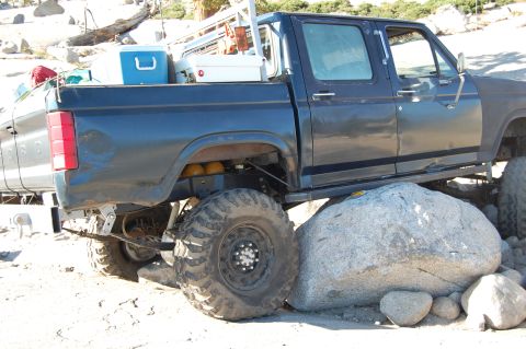 1993 Jeep Wrangler - This heavily modified pickup truck appears to be stuck on large rocks, with another vehicle nearby.