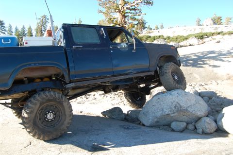1993 Jeep Wrangler - Modified pickup truck navigates rocky terrain under a clear sky.