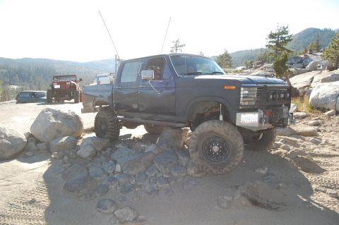1993 Jeep Wrangler - Modified Ford F-Series truck navigating a rocky trail with other vehicles present.