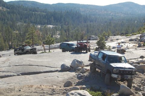 1993 Jeep Wrangler - Multiple off-road vehicles traverse a challenging rocky trail in a scenic, mountainous area.