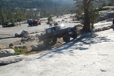 1993 Jeep Wrangler - Several off-road vehicles navigate a rocky, mountainous terrain under a clear sky.