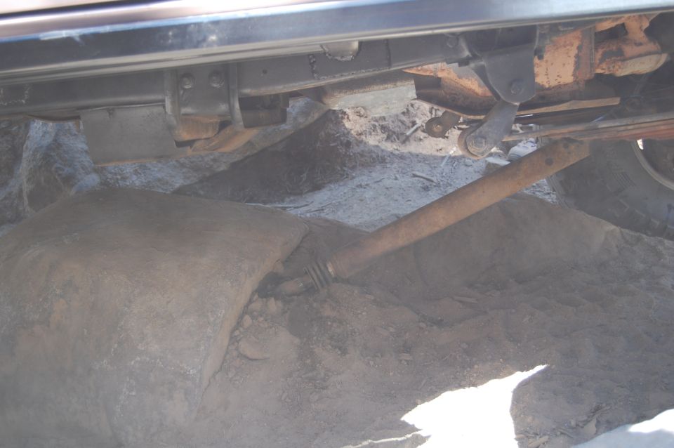 Undercarriage view showing suspension components and a large rock near the tire