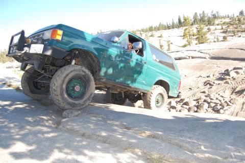 1993 Jeep Wrangler - Ford Bronco tackling a challenging off-road course with steep inclines and loose rocks.