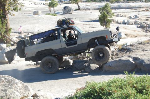 1993 Jeep Wrangler - Modified off-road SUV navigates a rocky trail with its doors removed.