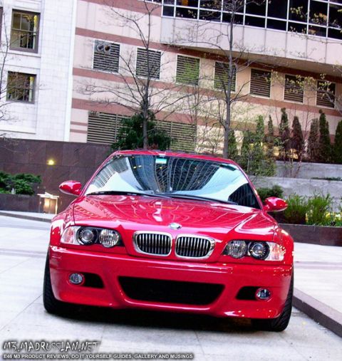 1998 Ford Crown Victoria - A red BMW M3 is parked in front of a modern building, its grille and headlights clearly visible.