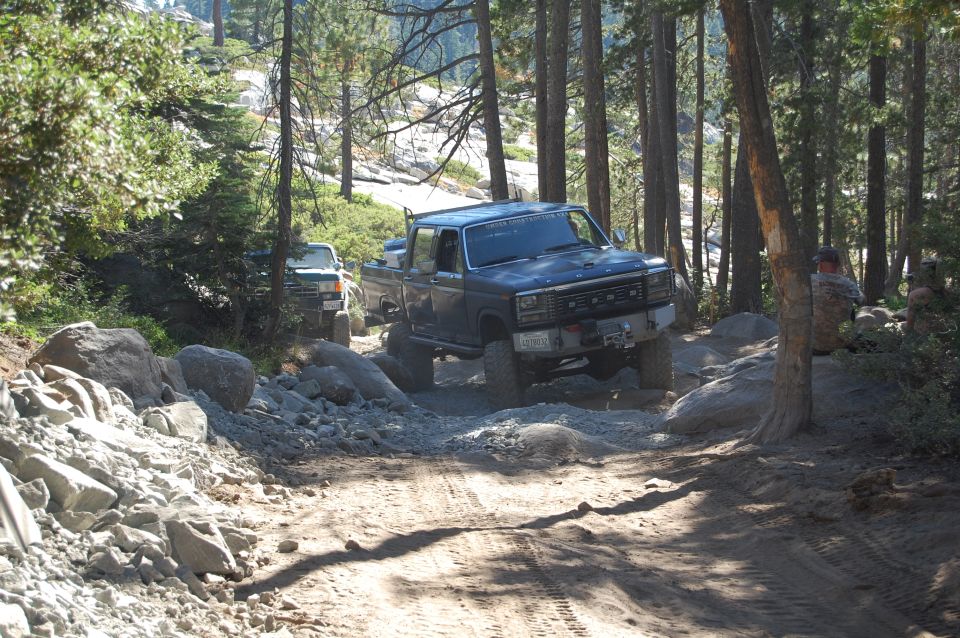 Ford pickup truck driving on a rocky trail with another truck behind it