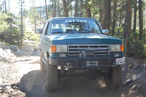 1993 Jeep Wrangler - This 1993 Ford Bronco navigates an off-road trail, its "ABUSED" windshield sticker a testament to its adventures.