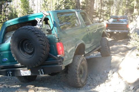 1993 Jeep Wrangler - Two off-road vehicles navigate a rocky path in a wooded area.
