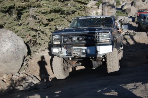 1993 Jeep Wrangler - This modified truck navigates a challenging off-road course, with other vehicles visible in the background.