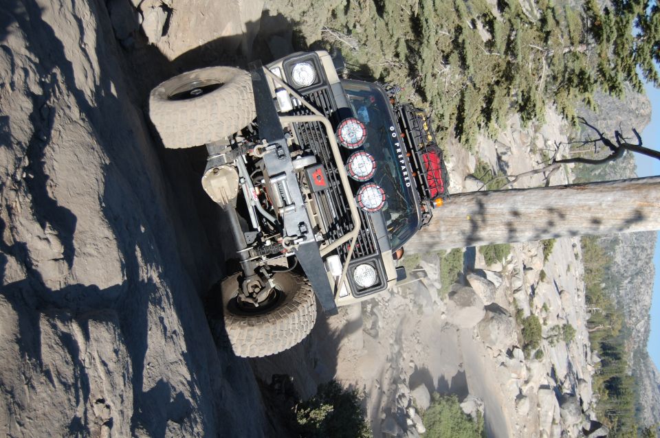 Tan off-road vehicle with winch and lights climbing a steep, rocky trail