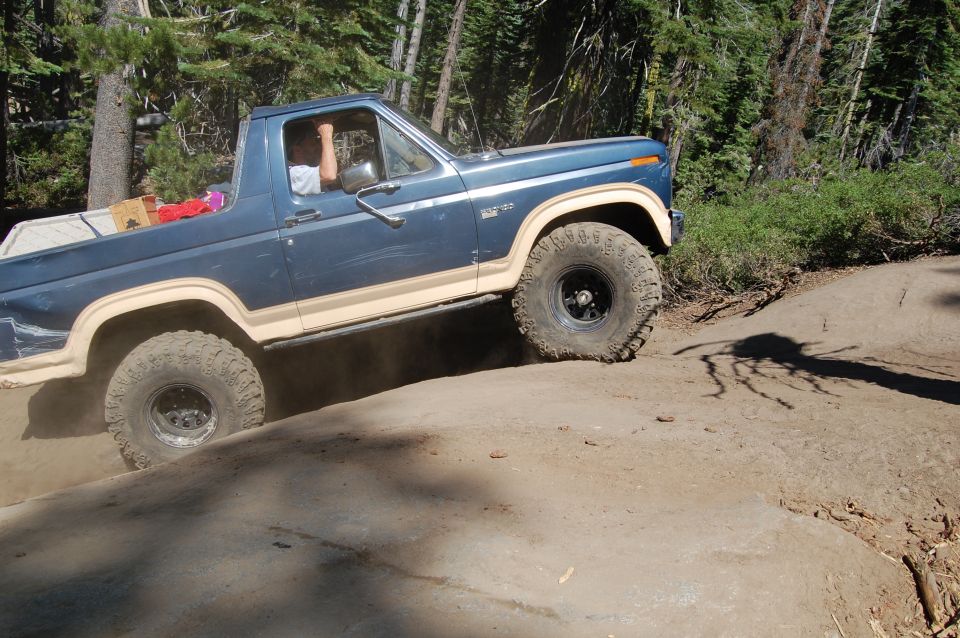 Blue pickup truck with tan trim off-roading on a dirt path