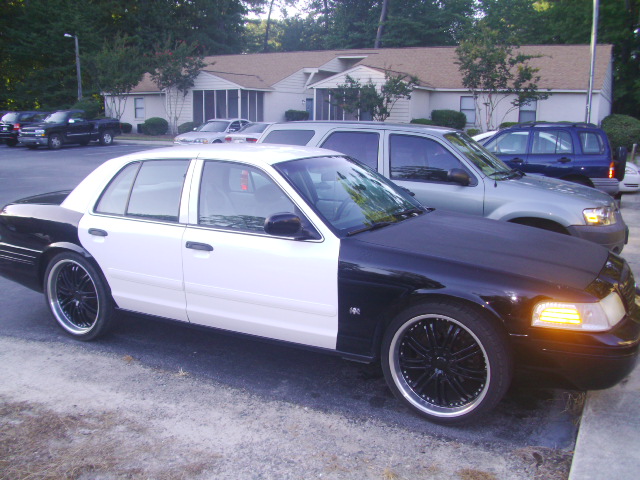 Car with black front and white rear, parked next to other vehicles