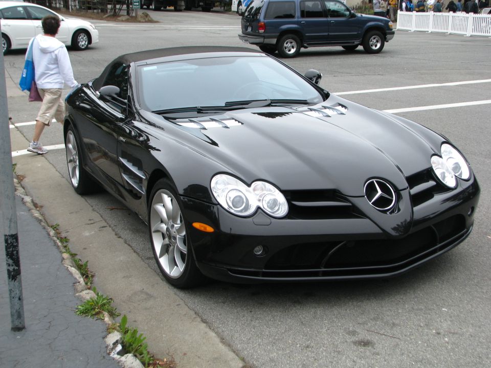Black convertible sports car, 3q-front view. Watermark reads SUPERMOTORS.NET