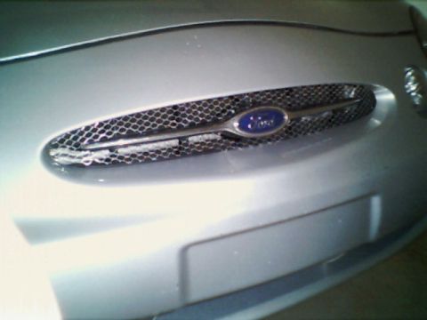 1998 Ford Taurus - Close-up of a silver Ford Taurus grille, showing the honeycomb mesh and Ford badge.