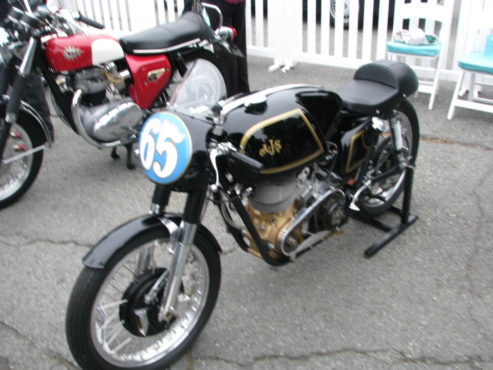 Black and gold motorcycle with number 65 on a blue circle on the front fairing, parked next to a red and white motorcycle
