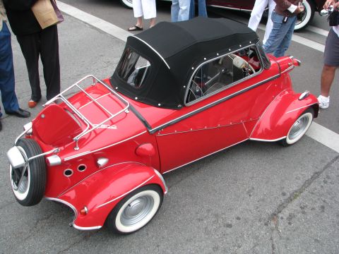 2004 Chrysler PT Cruiser - A small, red, two-seater convertible microcar with a black soft top is parked on a street.