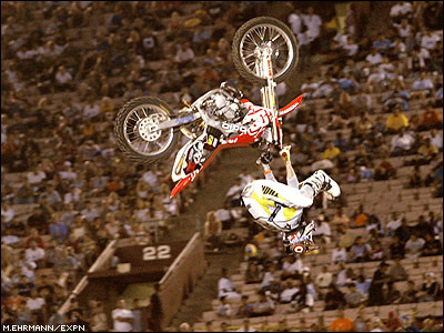 1990 Ford Bronco - A motocross rider is captured mid-air performing a stunt with the stadium crowd in the background.