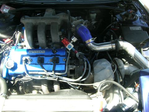 1995 Ford Probe - Close-up of a modified engine bay, a blue Mazda engine with turbo components and custom piping.