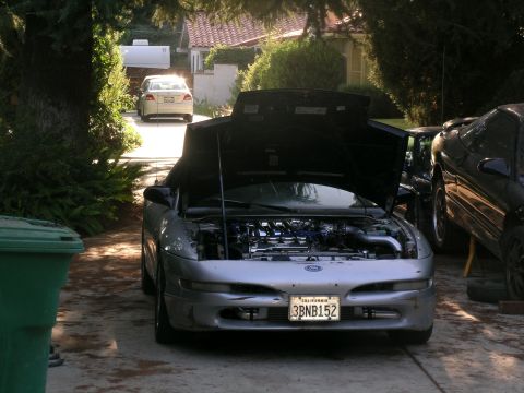 1995 Ford Probe - A silver 1995 Ford Probe is parked in a driveway with its hood up, revealing the engine.