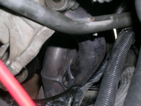 1995 Ford Probe - This image shows a close-up view of a vehicle's exhaust manifold and associated piping, with some wiring and hoses visible.