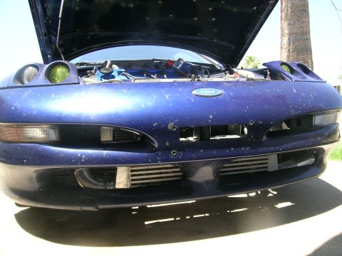 1995 Ford Probe - Front view of a blue Ford Probe with its hood open, revealing intercoolers and engine modifications. The vehicle's body style is characteri…