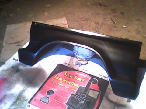 1978 Ford Bronco - A black fender panel is shown on a white surface next to a box for a stove board protector.