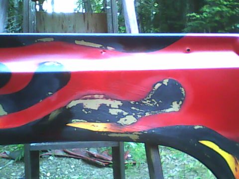 1978 Ford Bronco - A close-up of a damaged car door with flame graphics and peeling paint.