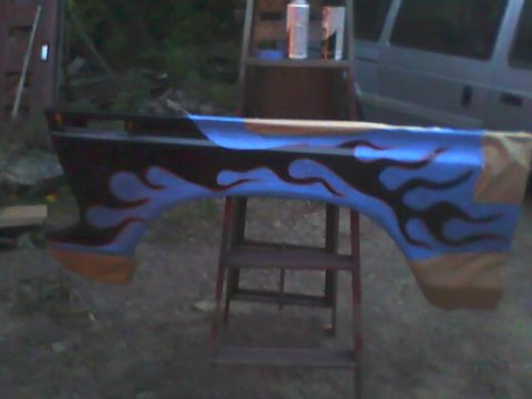 1978 Ford Bronco - A vehicle fender with a custom flame paint job is displayed outdoors.