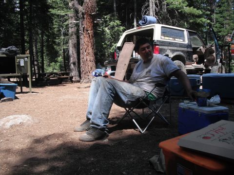 1991 Ford Bronco - A man relaxes in a chair next to a 1991 Ford Bronco at a campsite.
